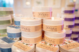 Multiple containers of 'The Lily Garden' hand cream stacked together with a blurred background.