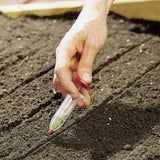 Hand holding a soil testing device over garden soil
