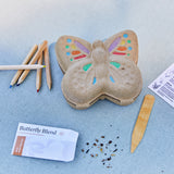 Butterfly-shaped Curious Critters Garden Kit with colored icing, markers, and a seed packet on a blue surface
