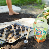 Seed ball kit with seed balls and a small shovel on garden soil