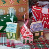 Small house-shaped grow kits with colorful labels on a plaid fabric background.