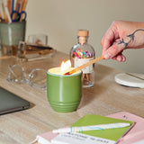 Person lighting a green candle with a wooden match on a desk. Garden Vibes Candle/Planter 2-in-1