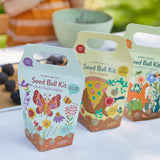 Three seed ball kit boxes with colorful designs on a white surface.