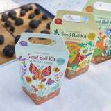 Seed ball kits with colorful packaging featuring butterfly and flower designs on a white surface.