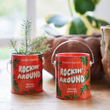 Two red buckets labeled 'Rockin' Around' with plants on a wooden surface.