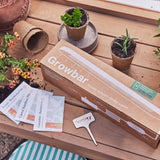 Growbar gardening kit on a wooden surface with plants and seed packets. Smart Growbar
