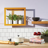Kitchen counter with cookbooks, apples, and a pot, featuring a yellow frame on the wall. Smart Standard Growframe