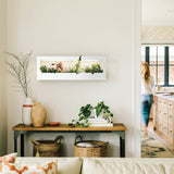 Living room with a wall-mounted plant display, wooden table, and sofa. Smart Landscape Growframe