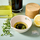 Peel, Grate & Prep Dish with olive oil, thyme, and salt on a light blue surface