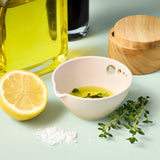 Peel, Grate & Prep Dish with liquid, lemon, herbs, and a wooden container on a light green background