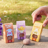 Three Easter Plops with animal illustrations and wildflower seed balls on a concrete surface with grass in the background.