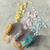 Three candy packages labeled 'Cheers', 'Yipple', and 'Bravo' with colorful square candies on a gray surface.