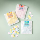 Three packages of flower seed confetti with scattered confetti pieces on a light green background
