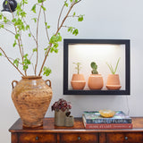 Decorative setup with a vase, plants, and books on a wooden surface. Modern Terracotta Grow Kits