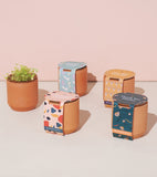 Set of Tiny Terracotta Kits with colorful labels on a light pink background