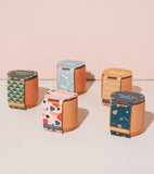 Tiny Terracotta Kits with colorful labels on a light pink background