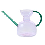 Clear glass watering can with green handle and spout on a white background