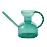 Green glass watering can on a white background