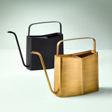 Two watering cans, one black and one gold, on a light gray background