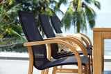 Outdoor furniture set with black chairs and a wooden table against a palm tree backdrop.