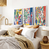 Modern Colorful Floral Matisse Wall Art Set  on a wall above a bed with pillows and a lamp.
