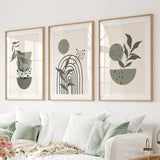 Three framed prints with plant and rainbow designs on a wall above a sofa.