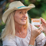 Woman wearing a straw hat with a blue band, holding MILK & HONEY SOAP SLICE 5 oz.