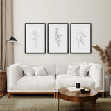 Modern living room with a white sofa, wooden coffee table, and floral wall art.