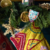 Decorative gift with a colorful label, greenery, and dried oranges on a blue background Seed Pops - Pollinator