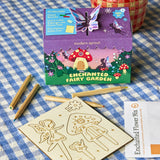 Enchanted fairy garden kit with packaging, wooden tools, and flower mix on a checkered tablecloth.