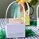 Small gardening tools in a decorative holder with 'Grow Flowers for Pollinators' text on a checkered tablecloth.