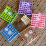 Five transparent seed trays with circular compartments on a wooden surface.