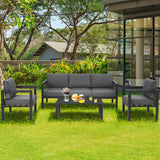 Outdoor patio set with gray cushions on a grassy area with trees and a building in the background.