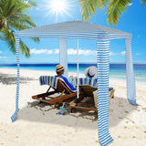 Two people sitting under a striped beach canopy on a sunny beach with palm trees.
