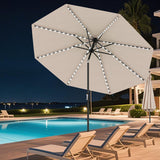 Beige patio umbrella with LED lights on a poolside deck at night.