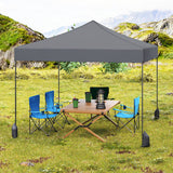 Outdoor setting with a gray canopy over a wooden table and blue chairs in a grassy area.