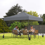 Family sitting at a dining table under a large gray outdoor canopy in a garden setting.