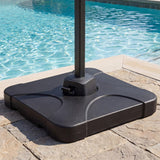 Black patio umbrella base on a stone surface with a pool in the background