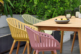 Outdoor setting with colorful chairs around a wooden table.