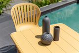 Three gray vases on a yellow table by a poolside