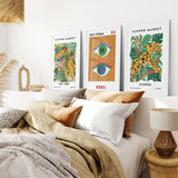 Bedroom with Modern Abstract Flower Market Set of 3 Piece on the wall and a bed with pillows and blankets.
