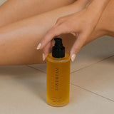 Hand holding a yellow bottle labeled 'DAYDREAM' near a leg on a neutral background