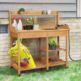Wooden gardening workbench with plants, tools, and supplies against a brick wall.
