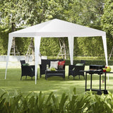 Outdoor setting with a white canopy tent, patio furniture, and a grill in a garden.