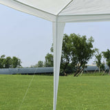 White canopy tent with a clear sky and green trees in the background