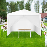 White canopy tent set up on a grassy area with floral arrangements and chairs.