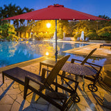 Red umbrella over a poolside table and chairs at night.