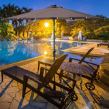Poolside area with lounge chairs, table, and umbrella at night.