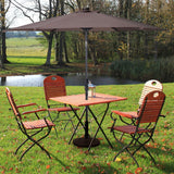 Outdoor patio set with table and chairs under a large umbrella in a park setting.