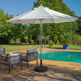 Outdoor patio umbrella and furniture by a pool with greenery in the background